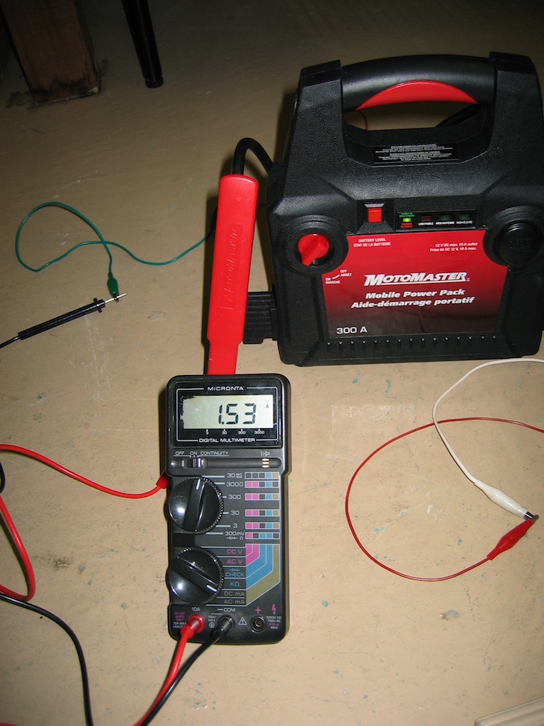A multimeter showing a reading of 1.53 amps. There is a Motomaster 12 volt battery pack in the background.